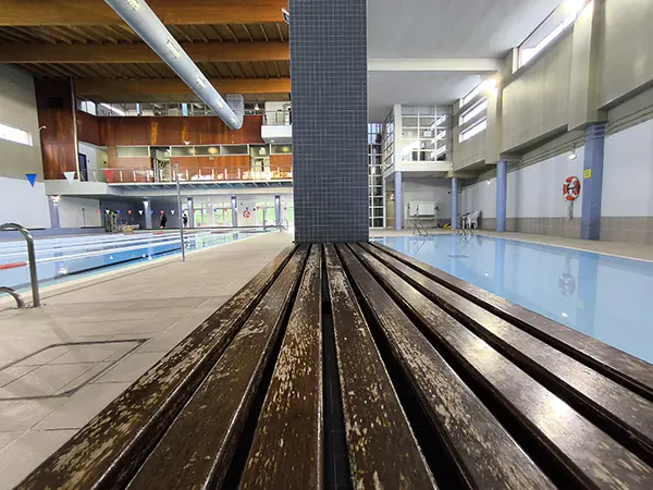 Vista de las piscinas de nado y aprendizaje, con detalle del pasillo y el banco de madera que las separa