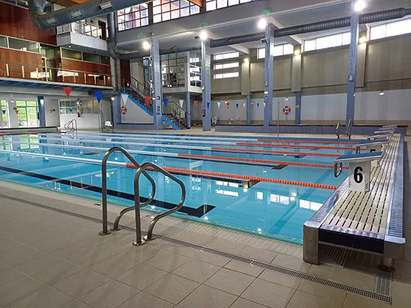 Vista lateral de la piscina de entrenamiento, con barandillas de acceso y plataformas de lanzamiento