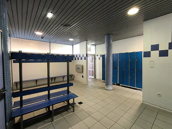 Vestuarios con bancos con perchas, taquillas y un cambiador de pañales plegable de pared