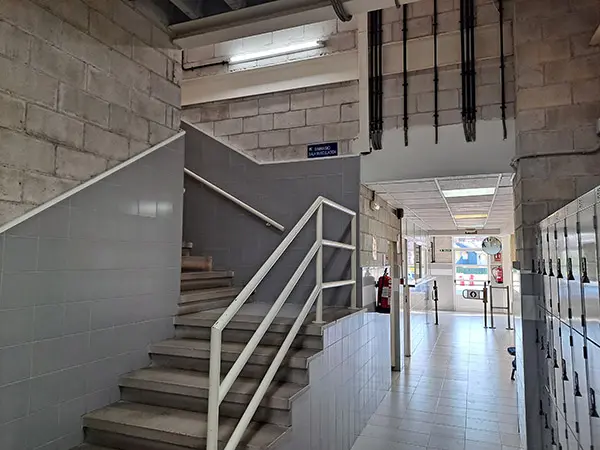 Escalera de acceso al piso superior. Pasillo de acceso a vestuarios y taquillas