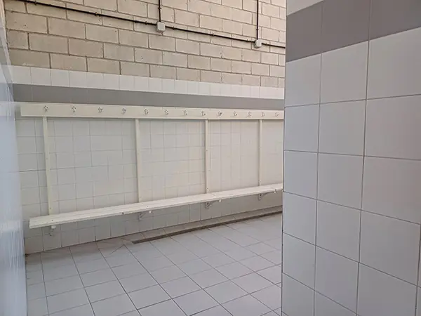 Interior de un vestuario. Perchas en una pared y un banco