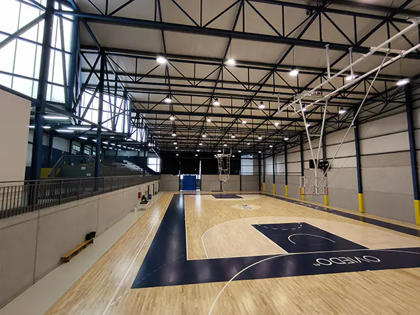 Pista polideportiva, vista desde el fondo, con las gradas en un lateral