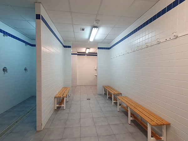 Interior de uno de los vestuarios, duchas y bancos. 