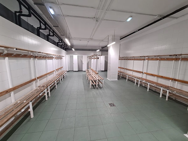 Interior de los vestuarios, con bancos de madera con perchas adosados a las paredes