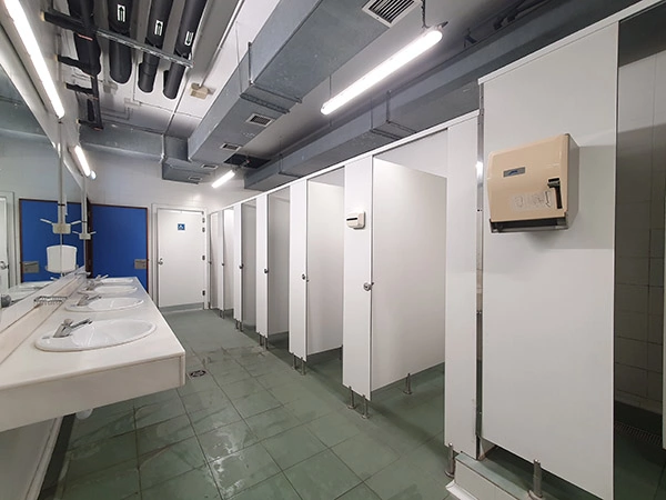 Interior de los aseos, con una fila de cabinas de retrete a la derecha y lavabos a la izquierda