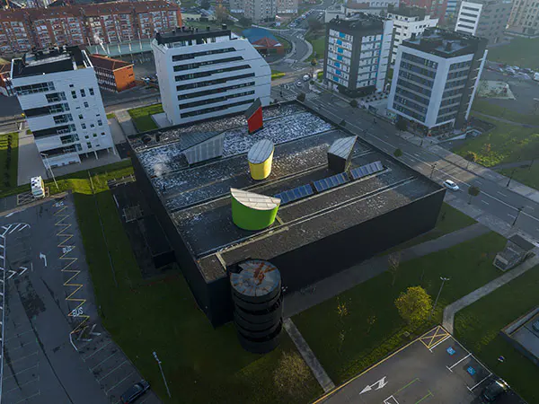 Vista aérea del Centro Deportivo Corredoria Arena, con grandes lucernarios de diversas formas y colores en el tejado