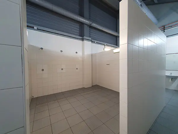 Vestuario azulejado, con una zona de duchas y aseos