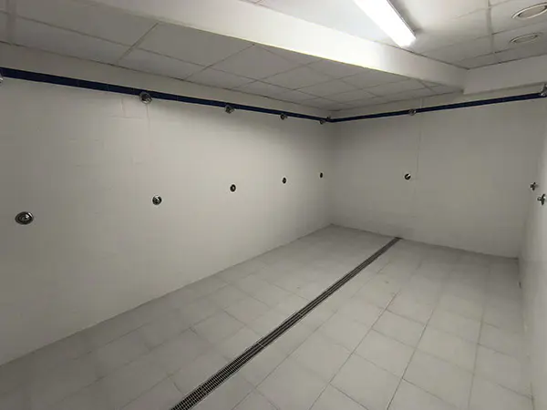 Zona de duchas de los vestuarios, con suelo y paredes de azulejos