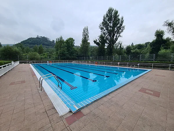 vista de la piscina desde una esquina con escaleras de acceso en primer plano