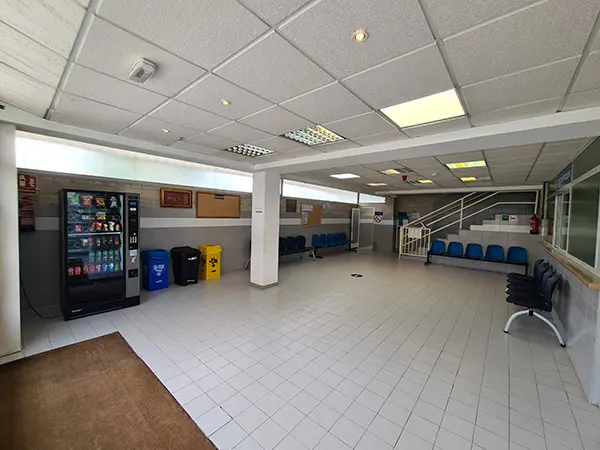 Vestíbulo de la instalación. Zona de recepción con filas de asientos y escalera de acceso a planta superior 
