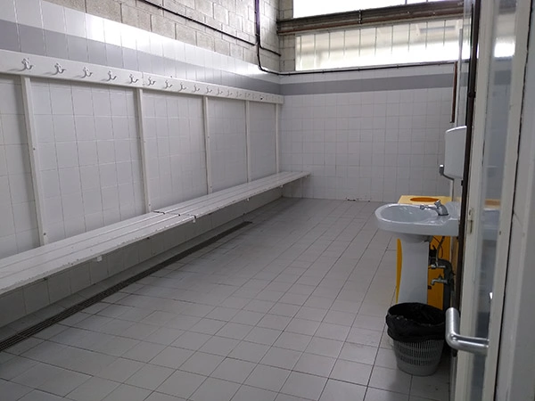 Interior de uno de los vestuarios. Lavabo y fila de bancos con perchas