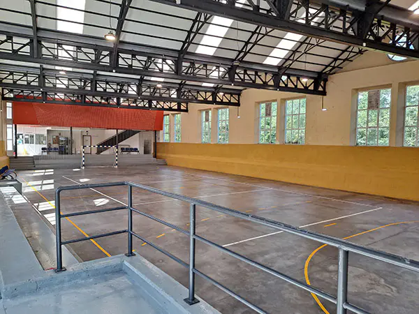 Pista polideportiva con la recepción y entrada al fondo. Zona para publico en primer plano