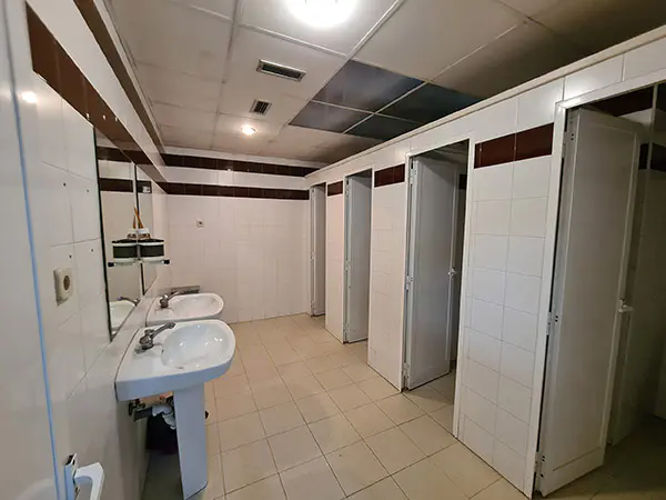 Aseos, con cabinas de retretes a la derecha y lavabos y espejos a la izquierda