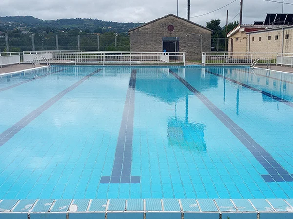Vista frontal de la piscina principal, con sus 6 calles y el edificio de instalaciones al fondo