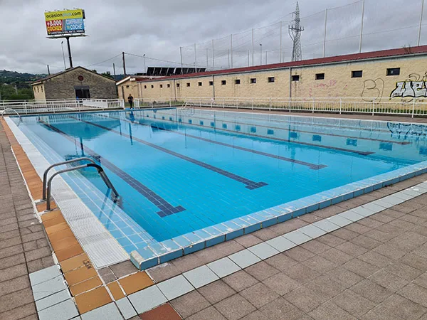 Panorámica de la piscina principal, con vista de los edificios circundantes y barandillas de acceso