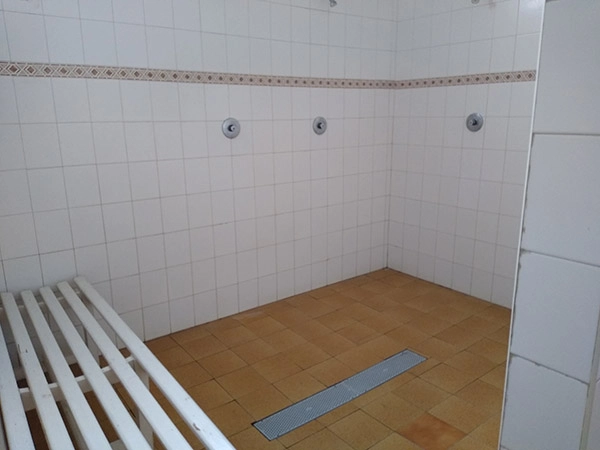 Sala de duchas con banco y paredes de azulejos