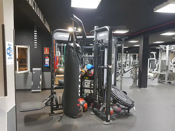 Sala de musculación, con máquina de musculación en primer plano y otras máquinas deportivas al fondo