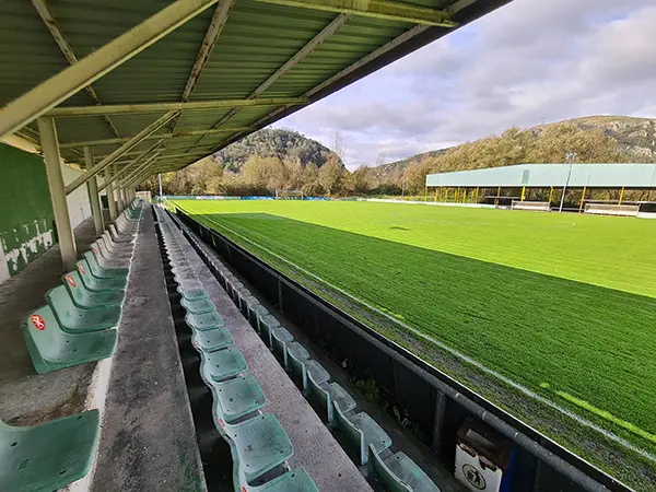 Vista lateral de tres hileras de la grada cubierta del campo de fútbol que alberga 350 espectadores sentados.