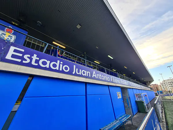 Vista lateral y desde abajo de la grada cubierta del estadio y del mensaje de bienvenida en letras blancas sobre fondo azul
