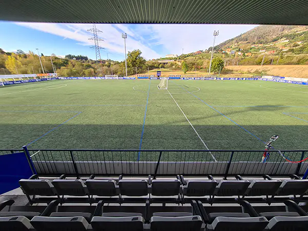 Campo de juego visto desde la grada. Se ve parte de la cubierta de la grada y asientos del palco