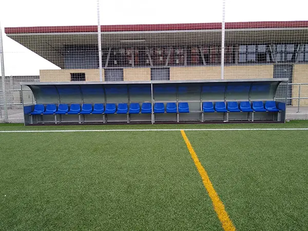 Vista de frente del  banquillo de suplentes y equipo técnico con cubierta metalizada y asientos azules
