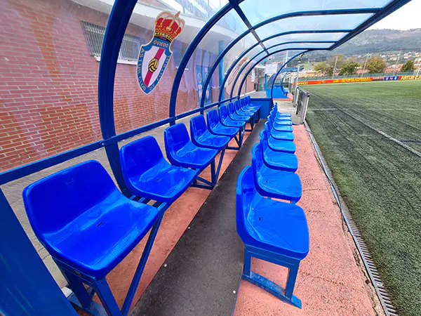 Vista de uno de los banquillos con detalle de los asientos y su estructura metálica transparente superior, con un escudo