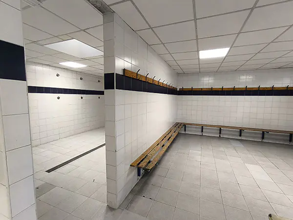 Interior de los vestuarios. A la izquierda, zona duchas y a la derecha, bancos y percheros de madera