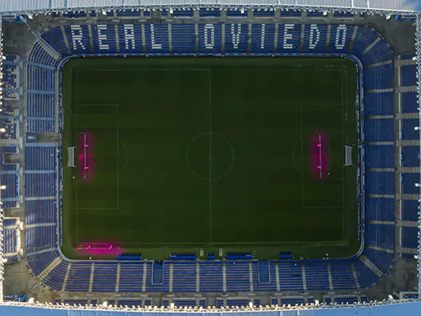 Campo de juego y sus tribunas de color azul tomado desde la altura. Escrito en una tribuna, con letras blancas: Real Oviedo