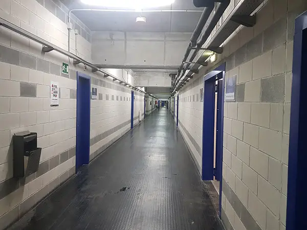 Largo pasillo interior del estadio con diferentes accesos a vestuarios jugadores y árbitros, capilla, sala de prensa y otros
