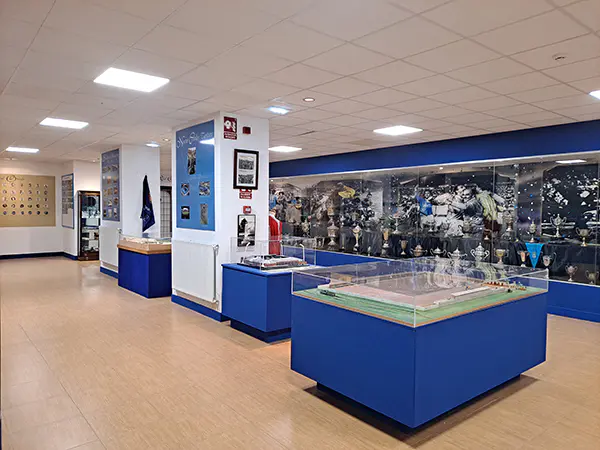 Museo con tres vitrinas expositoras maquetas del estadio, detrás vitrinas con los trofeos ganados por el club