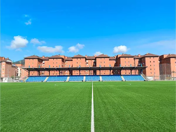 Vista lateral y a pie de campo del terreno de juego, con las gradas y edificios al fondo