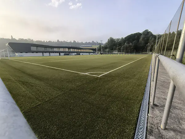 Panorámica de un campo de fútbol 11 desde uno de los córneres, con las gradas al fondo