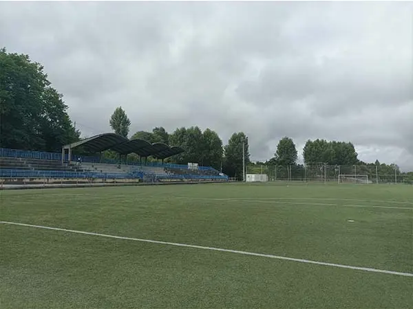 Vista parcial a pie de campo del terrreno de juego, con las gradas cubiertas a un lado y una portería al fondo