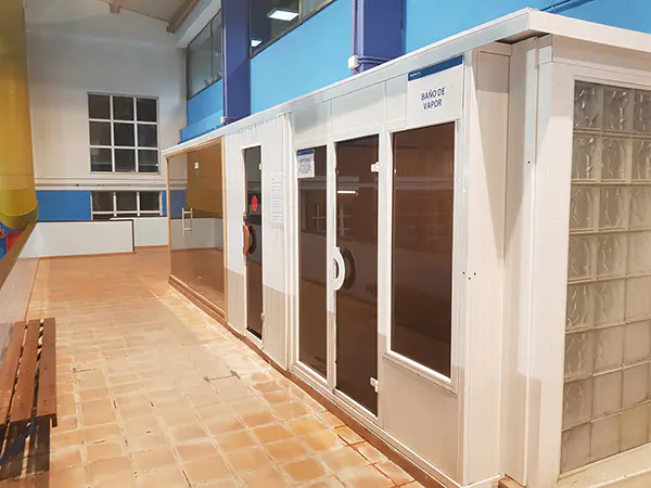 Salas de baños de vapor y sauna, con el pasillo de acceso y un banco de madera frente a ellas