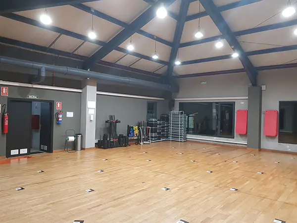 Vista en detalle de una zona de la sala de actividades dirigidas, con un gran espejo y diversos accesorios deportivos