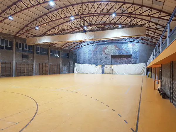 Panorámica de la pista polideportiva, con portería de fútbol sala, grada lateral y rocódromo al fondo
