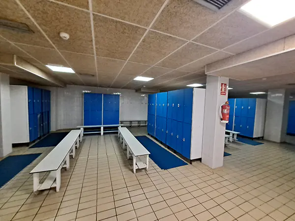 Vista general del interior de los vestuarios, con taquillas y bancos de madera