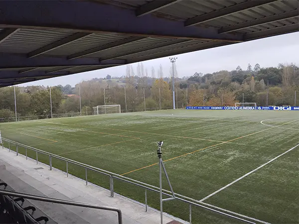 Campo de fútbol visto desde las gradas distinguiéndose la cubierta metalizada y las barandillas plateadas que lo separan