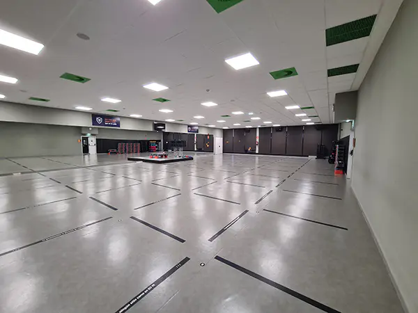 Panorámica general de una de las salas de actividades dirigidas, con diversas pantallas y tarima para el instructor