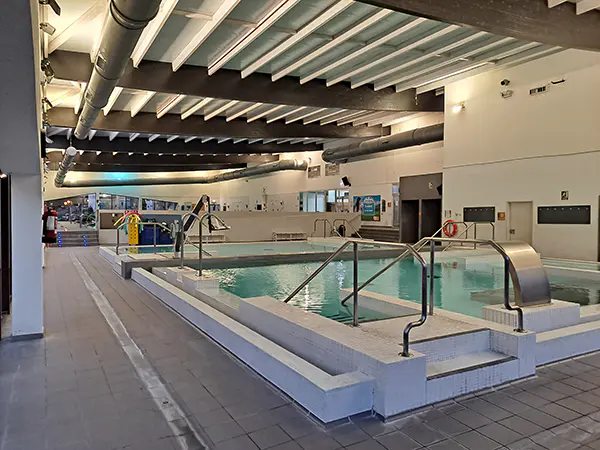 Piscina de spa, con escalerillas y barandillas de acceso y grúa con asiento para baño de personas con movilidad reducida