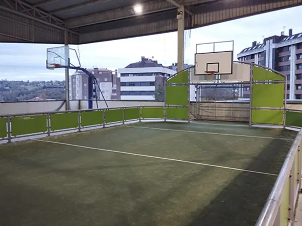 Pistas exteriores de baloncesto cubiertas, con canastas. Vista de edificios al fondo