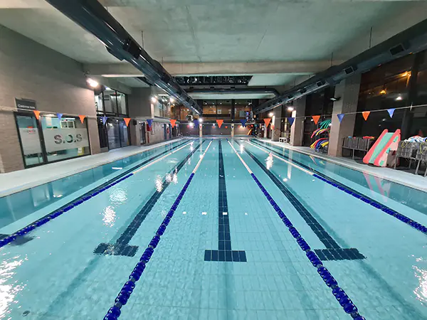 Panorámica frontal de la piscina de entrenamiento climatizada, con vista de las calles y la sala de socorrismo a la izquierda
