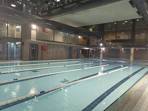 Panorámica lateral de la piscina de entrenamiento climatizada, con vista de sus calles y vista parcial del piso superior