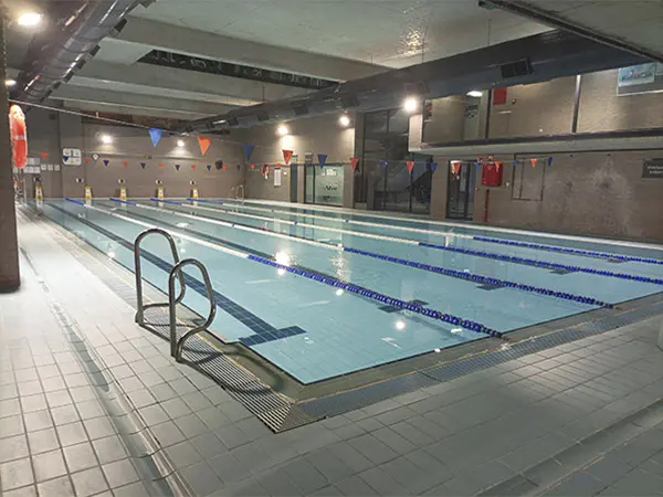 Panorámica lateral de la piscina de entrenamiento climatizada, con las escalerillas de acceso