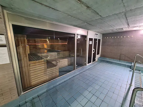 Sala de sauna, con vista lateral de los bancos de madera de su interior a través de la cristalera exterior