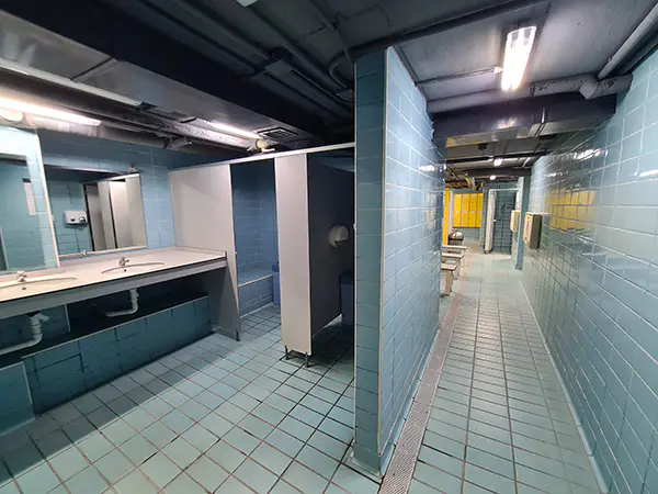 Lavabos y baños del vestuario femenino, con vista del pasillo que lleva a las taquillas, al fondo