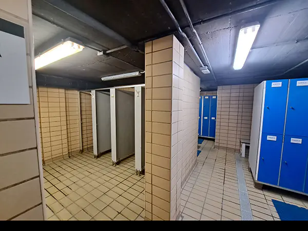 Interior del vestuario masculino, con vista parcial de las taquillas y las duchas