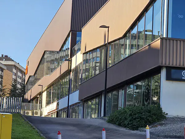 Exterior del centro deportivo, con una vista de la parte lateral del edificio principal y un camino de acceso