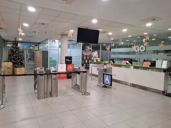 Vestíbulo del centro deportivo, con los tornos de acceso y el mostrador de recepción