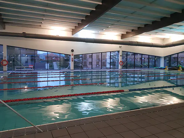 Panorámica lateral de la piscina de nado, con amplios ventanales con vistas al exterior